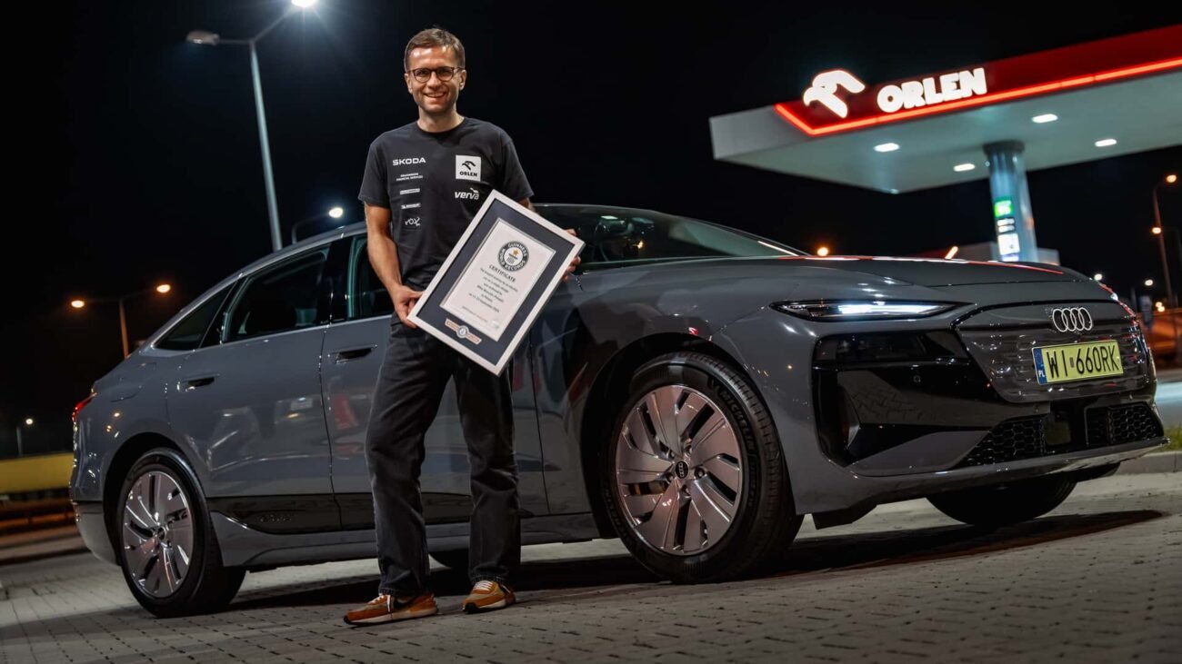 Vyras prie Audi elektromobilio laiko įrėmintą dokumentą degalinėje