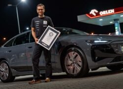 Vyras prie Audi elektromobilio laiko įrėmintą dokumentą degalinėje