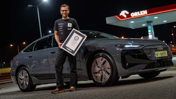 Vyras prie Audi elektromobilio laiko įrėmintą dokumentą degalinėje