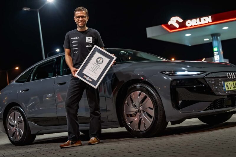 Vyras prie Audi elektromobilio laiko įrėmintą dokumentą degalinėje
