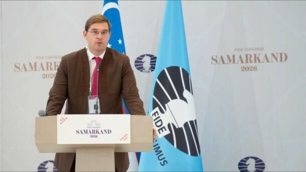 Vyras kalba prie tribūnos FIDE kongrese Samarkande
