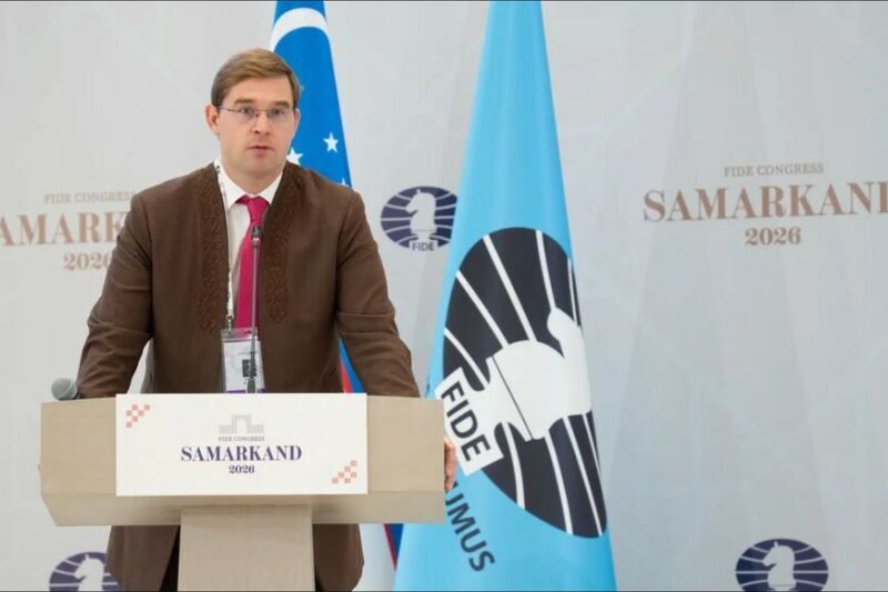 Vyras kalba prie tribūnos FIDE kongrese Samarkande