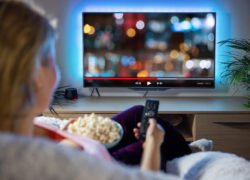 Žmogus namuose žiūri filmą per televizorių