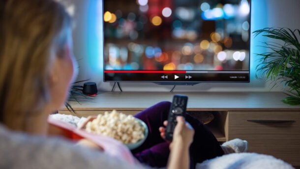 Žmogus namuose žiūri filmą per televizorių