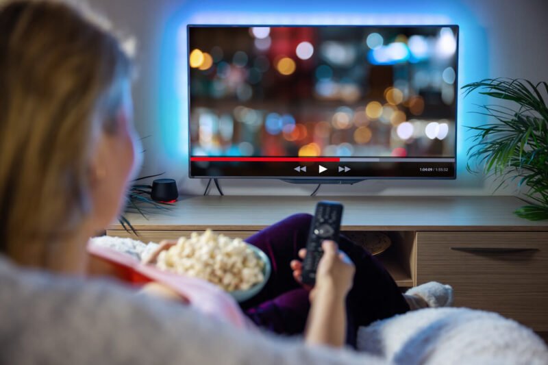 Žmogus namuose žiūri filmą per televizorių