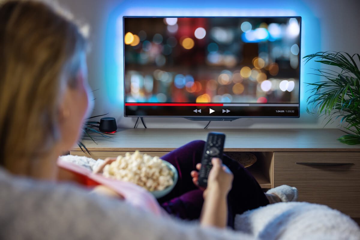 Žmogus namuose žiūri filmą per televizorių