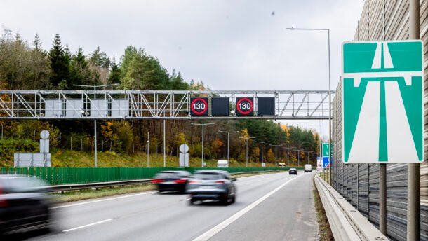 Greitkelyje važiuojantys automobiliai ir virš kelio rodomi 130 km/h ženklai