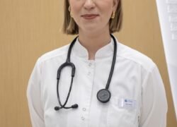 Gydytoja baltais chalatais su stetoskopu klinikos aplinkoje