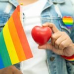 LGBT teisių pataisos Lietuvoje - žmogus su vaivorykštės vėliava ir širdies simboliu