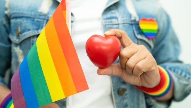 LGBT teisių pataisos Lietuvoje - žmogus su vaivorykštės vėliava ir širdies simboliu