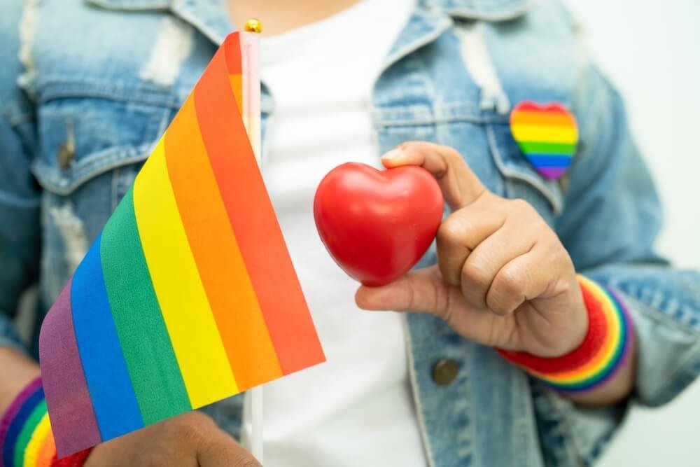 LGBT teisių pataisos Lietuvoje - žmogus su vaivorykštės vėliava ir širdies simboliu