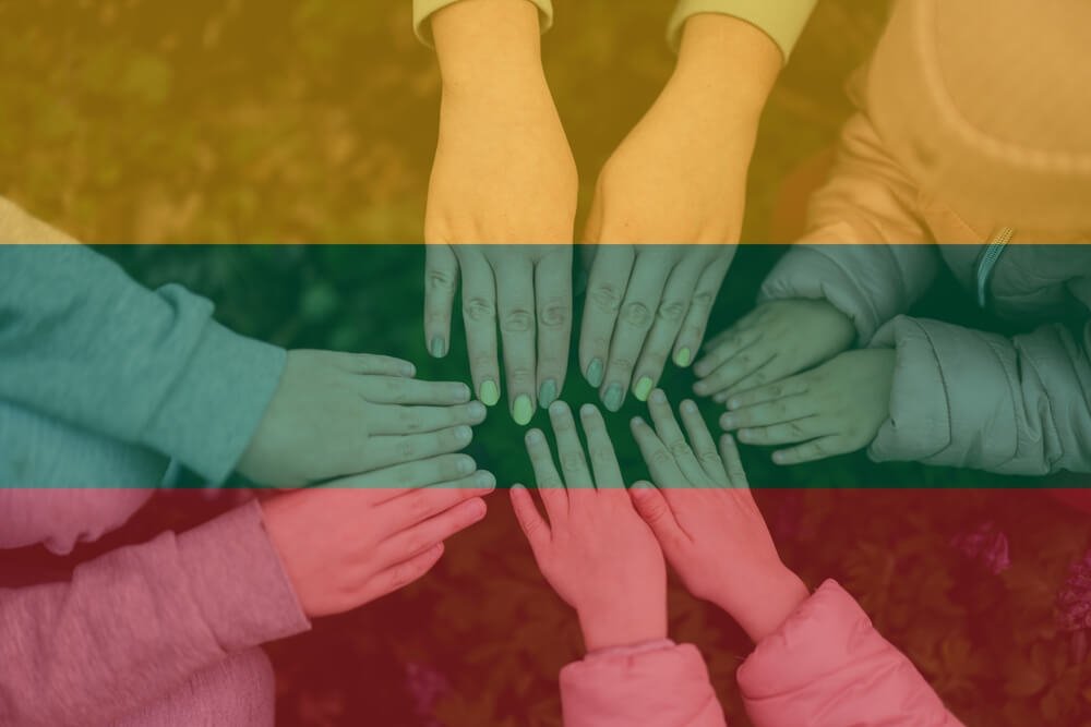 Mahiro Gamzajevo perspėjimas dėl tautinių mažumų integracijos - Lietuvos vėliavos spalvų fone susijungusios žmonių rankos