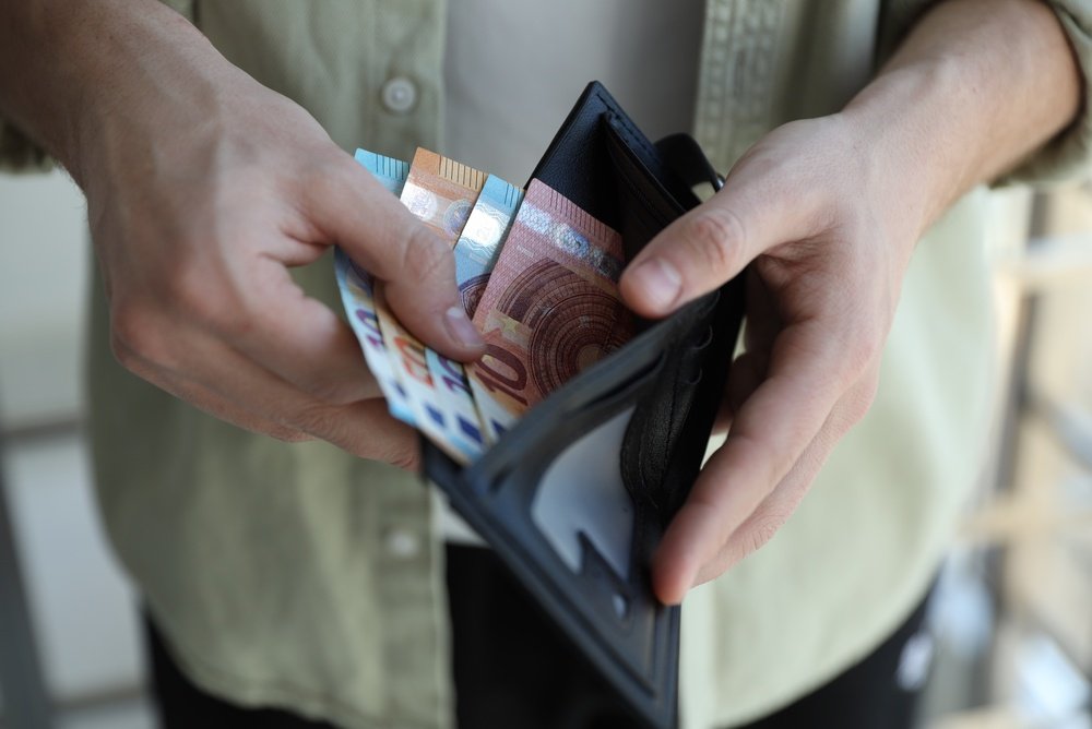 Rankos laiko atverstą piniginę su euro banknotais