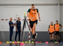 Oranžine liemene vilkintis dalyvis atlieka greičio pratimą salės aikštėje