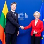 Du žmonės spaudžia rankas Europos Komisijos ženklu pažymėtame fone