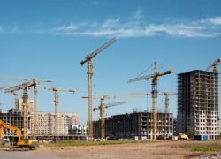 Statybų aikštelė su statomais daugiabučiais ir kranais