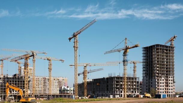 Statybų aikštelė su statomais daugiabučiais ir kranais
