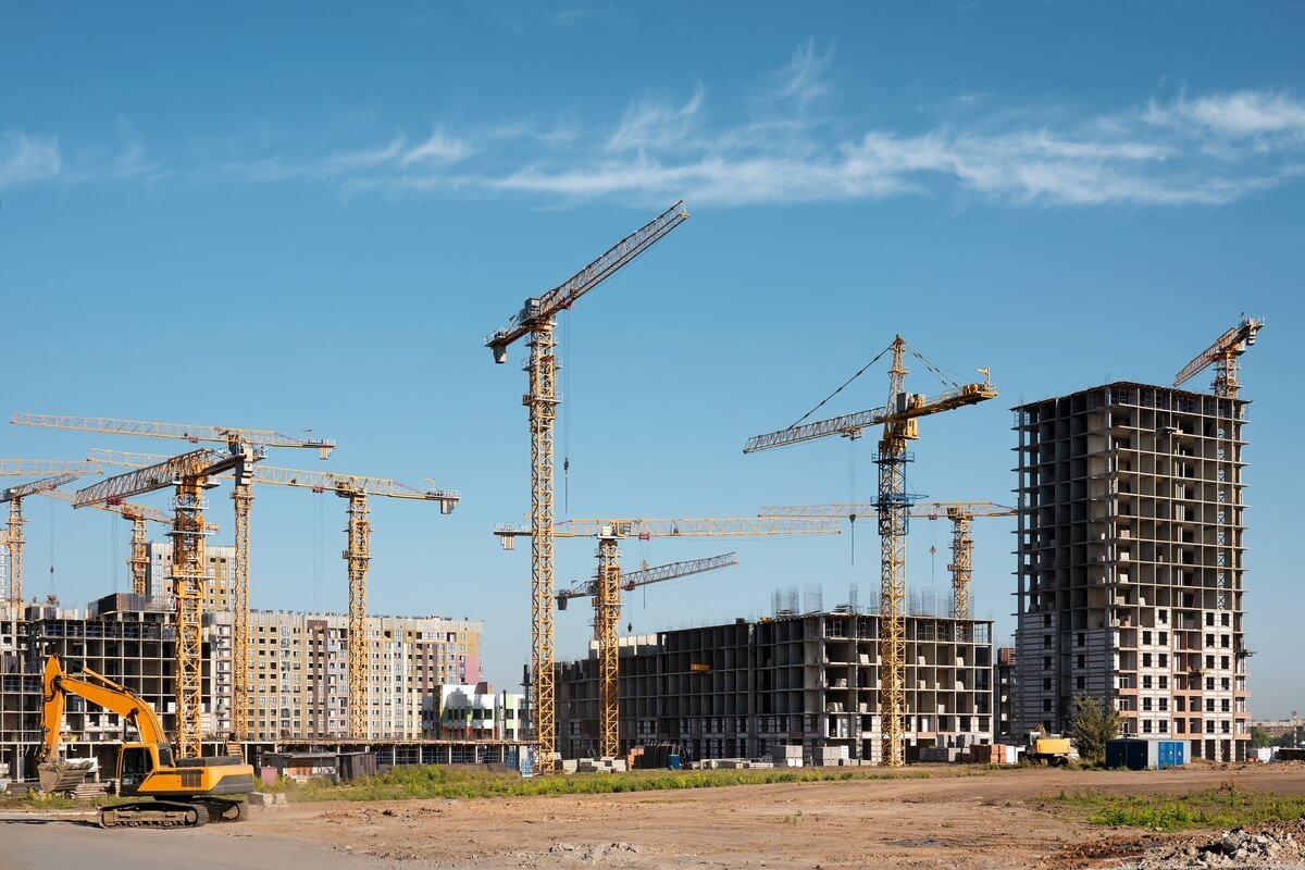 Statybų aikštelė su statomais daugiabučiais ir kranais