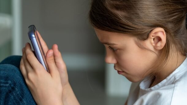 Vaikų saugumas internete - mergaitė naudojasi telefonu