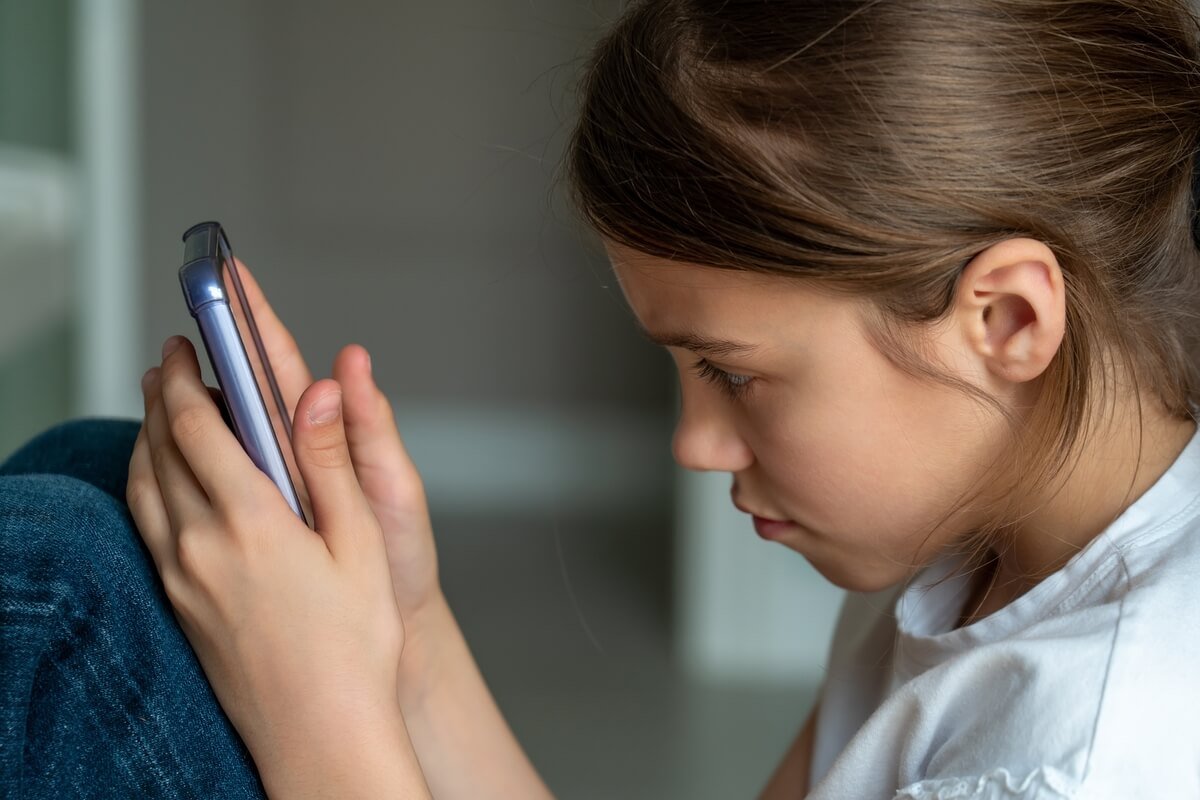 Vaikų saugumas internete - mergaitė naudojasi telefonu