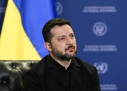 Volodymyras Zelenskis sėdi priešais Ukrainos vėliavą