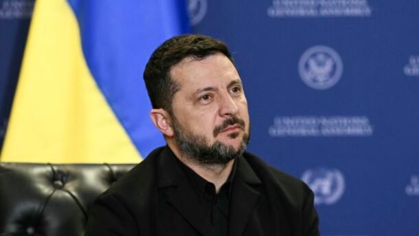 Volodymyras Zelenskis sėdi priešais Ukrainos vėliavą