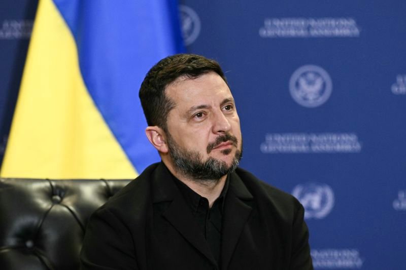 Volodymyras Zelenskis sėdi priešais Ukrainos vėliavą
