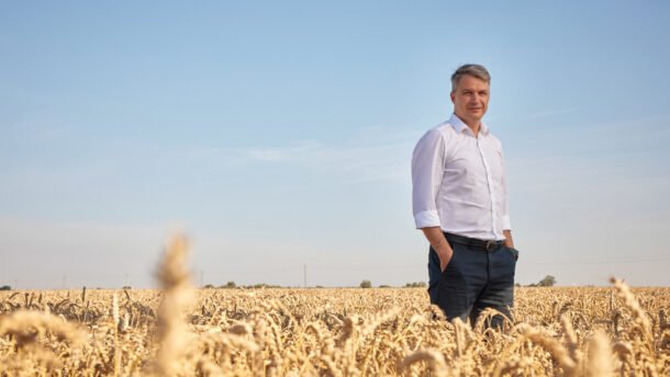 Vyras stovi auksiniame kviečių lauke po giedru dangumi