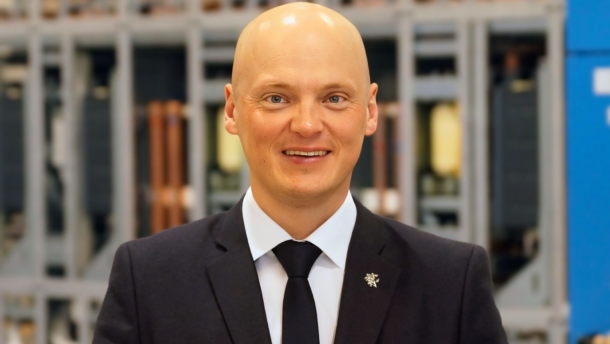 Besijuokiantis vyras su kostiumu pramoninėje aplinkoje