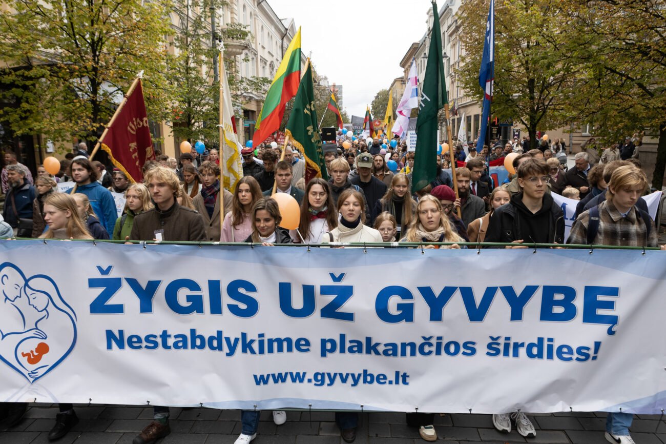 Žmonės Vilniaus gatvėje neša vėliavas ir žygio už gyvybę plakatą