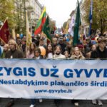 Žmonės Vilniaus gatvėje neša vėliavas ir žygio už gyvybę plakatą