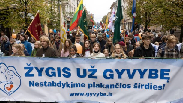 Žmonės Vilniaus gatvėje neša vėliavas ir žygio už gyvybę plakatą