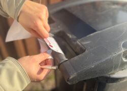 Rankos pritvirtina žymę prie juodo atliekų konteinerio dangčio