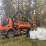Miške prie oranžinio sunkvežimio sukrauti didmaišiai su atliekomis