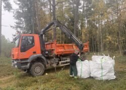 Miške prie oranžinio sunkvežimio sukrauti didmaišiai su atliekomis