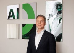 Verslo vyras stovi prie sienos su abstrakčiais paveikslais ir roboto atvaizdu
