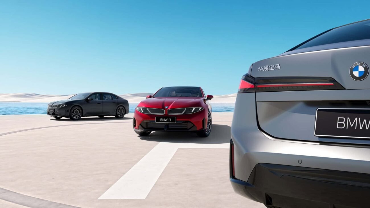 Trys BMW automobiliai pajūrio aikštelėje, priekyje matomas pilko automobilio galas