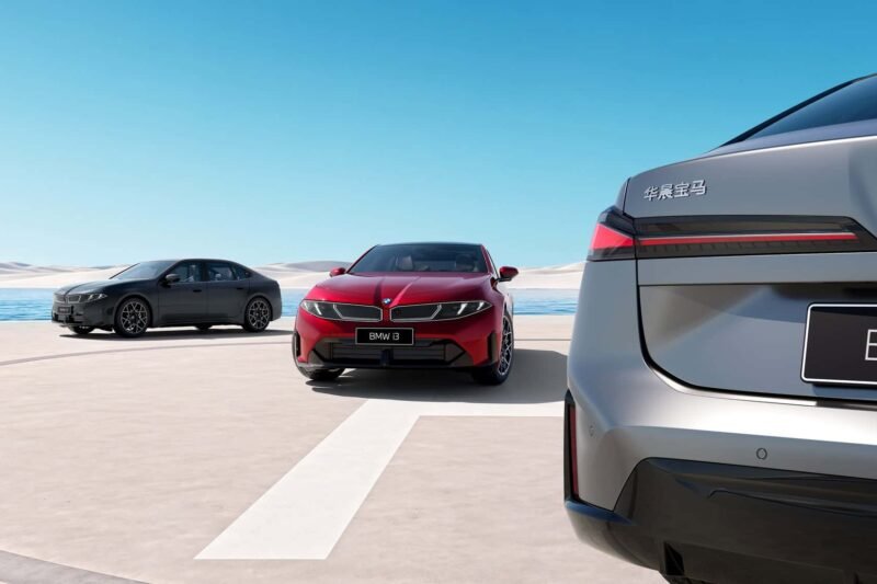 Trys BMW automobiliai pajūrio aikštelėje, priekyje matomas pilko automobilio galas