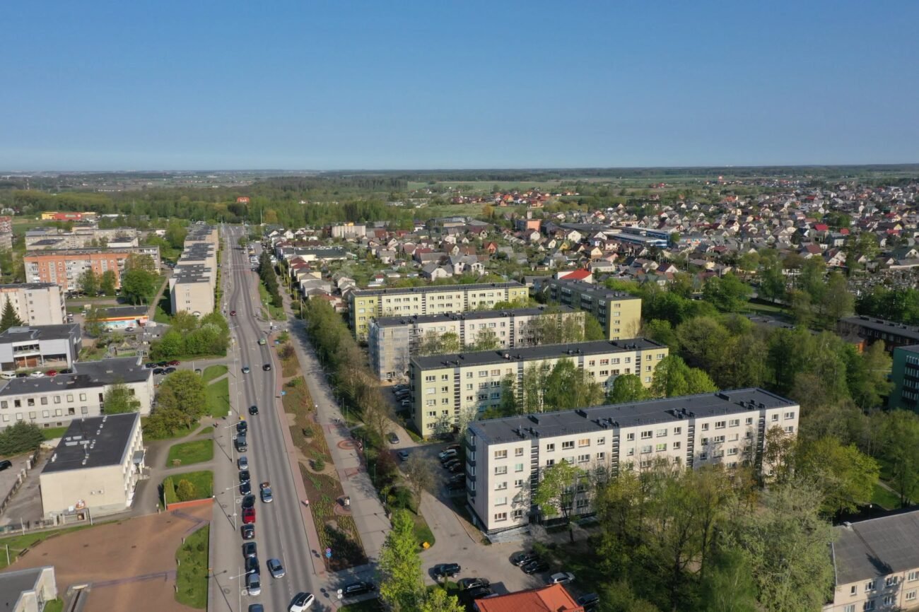 Iš paukščio skrydžio matomas daugiabučių rajonas su gatvėmis ir privačiais namais