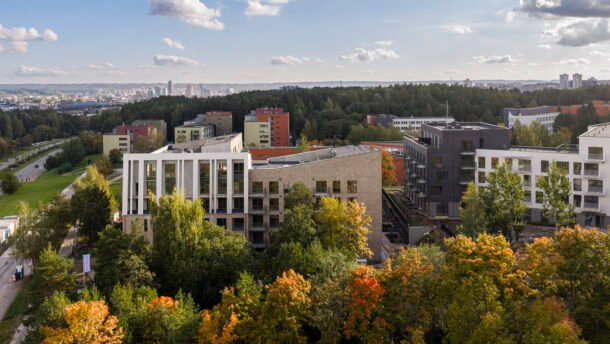 Miesto gyvenamieji namai apsupti medžių, tolumoje matoma tanki miesto panorama