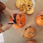 Rankomis skaptuojami Helovyno moliūgai, viename išraižytas veidas