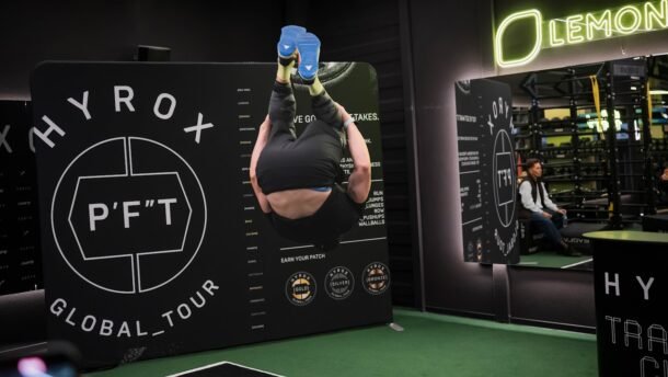 Sportuojantis žmogus HYROX treniruočių erdvėje šalia P’FT sienelės