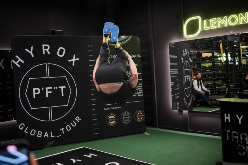 Sportuojantis žmogus HYROX treniruočių erdvėje šalia P’FT sienelės