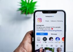 Ranka laiko išmanųjį telefoną su atidarytu Instagram profiliu
