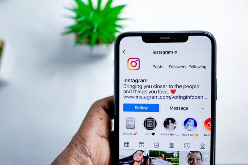 Ranka laiko išmanųjį telefoną su atidarytu Instagram profiliu