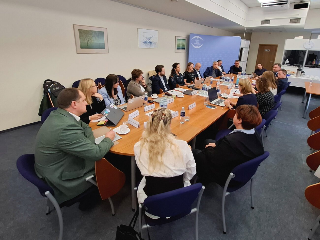 Institucijų atstovai susirinkę prie stalo dalyvauja darbiniame susitikime