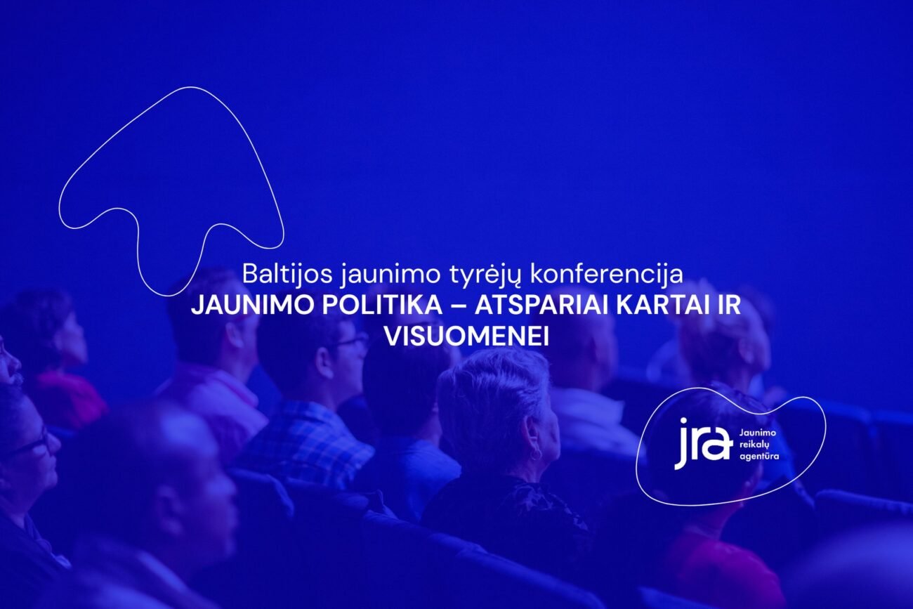 Mėlyna šviesa apšviesti konferencijos dalyviai sėdi auditorijoje