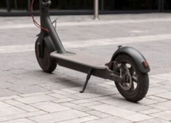 Juodas elektrinis paspirtukas stovi ant akmenimis grįstos aikštės
