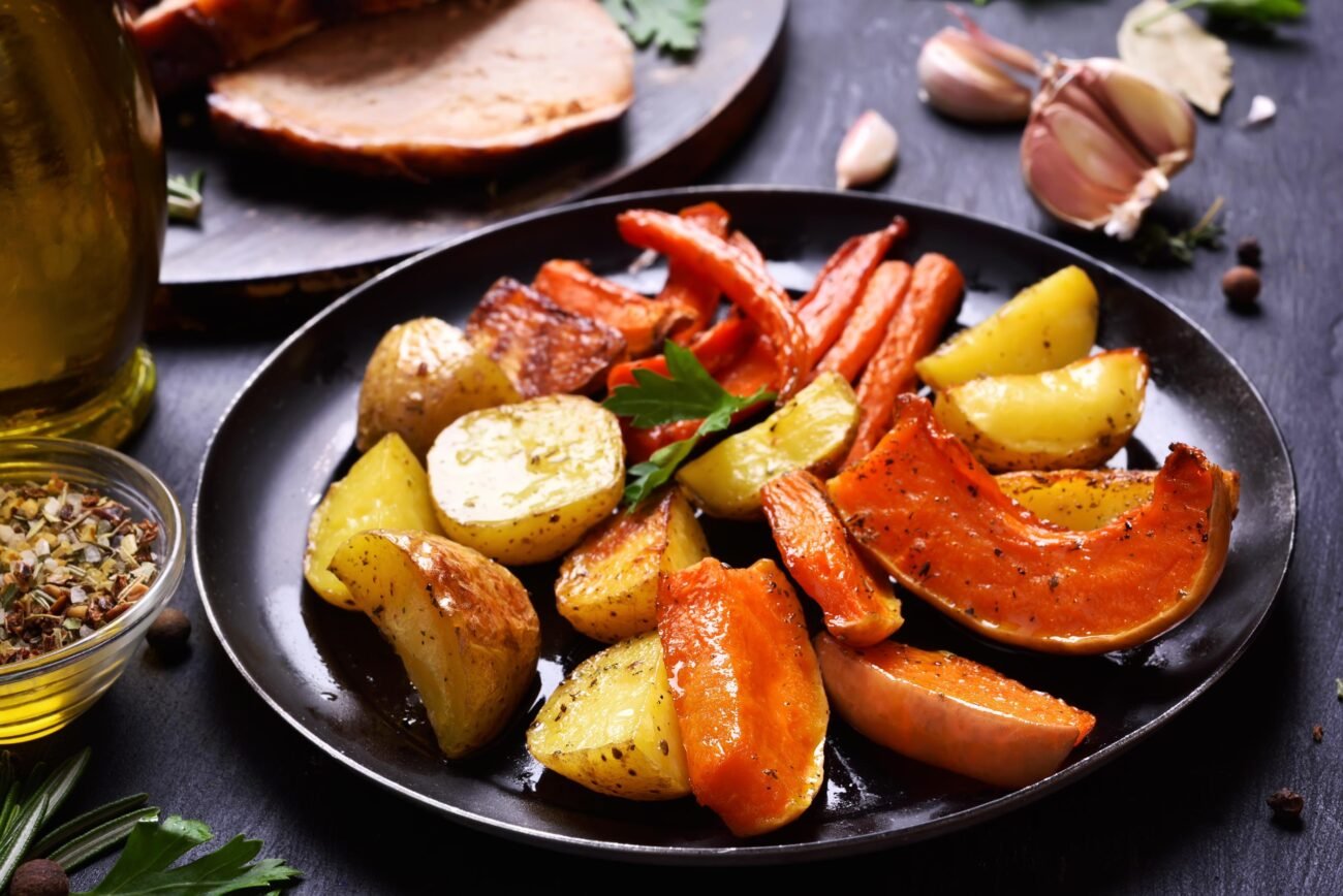 Keptos bulvės, morkos, moliūgas ir paprika juodoje lėkštėje