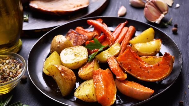 Keptos bulvės, morkos, moliūgas ir paprika juodoje lėkštėje